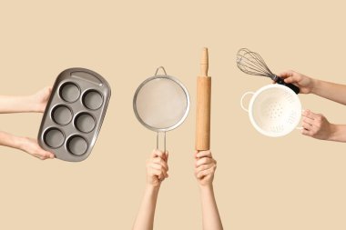 Merdaneli elek tutan kadın elleri, bej arka planda teneke ve çırpma kabı