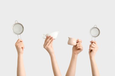 Beyaz arka planda süt sürahisi ile süzgeçleri tutan kadın eller