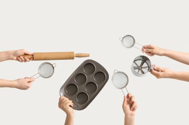 Beyaz arka planda merdane ve teneke fırın ile süzgeçleri tutan kadın eller