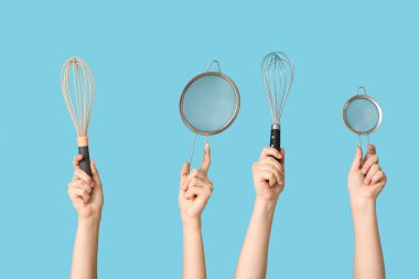 Mavi arka planda süzgeçleri ve çırpıcıları olan kadın elleri