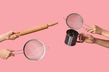 Female hands holding sieves with rolling pin on pink background clipart