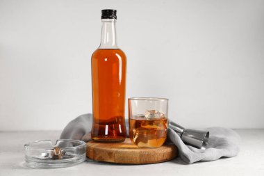 Şişe, bir bardak soğuk rom ve kül tablası beyaz arka planda. Yakın çekim.