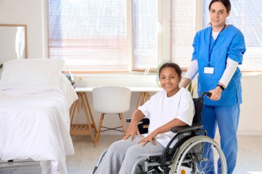 Genç Afro-Amerikan kız tekerlekli sandalyede, hastanede doktorla.