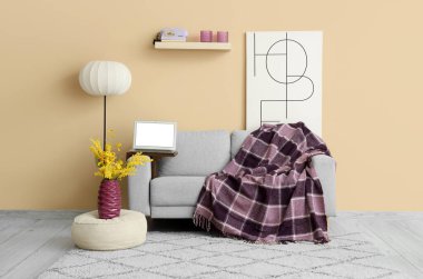 Kanepenin üzerinde ekose ve boş dizüstü bilgisayarla oturma odasının içinde.