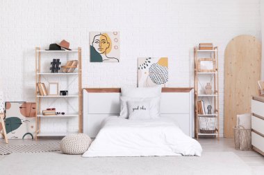 Yataklı, raf üniteli ve resimli ergen odasının içi.