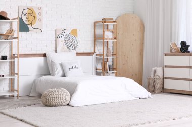 Yataklı, raf üniteli ve resimli ergen odasının içi.