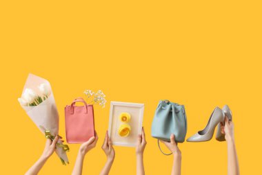 Sarı arka planda çiçek, ayakkabı ve el çantaları olan kartpostal tutan bir kadın. Uluslararası Kadınlar Günü için Alışveriş