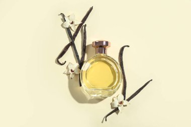 Renkli arka planda bir şişe parfüm, vanilya çubukları ve çiçekler.