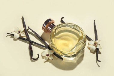 Renkli arka planda bir şişe parfüm, vanilya çubukları ve çiçekler.