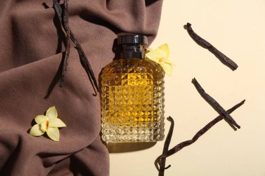 Renkli arkaplanda parfüm şişesi, vanilya çubuğu ve kumaş kompozisyonu