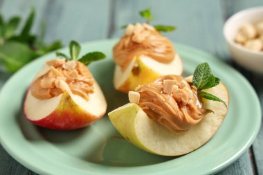 Lezzetli elma dilimleri, fındık ezmesi ve nane yapraklı tabaklar, yakın plan.