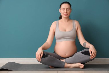 Genç hamile kadın spor salonunda yoga yaparken meditasyon yapıyor.