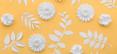 Paper flowers and leaves on yellow background