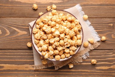 Tahta arka planda gevrek patlamış mısır kasesi.