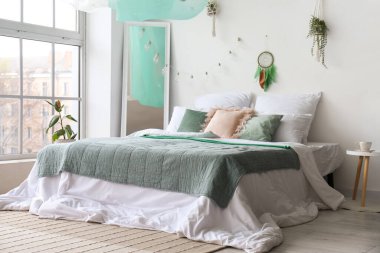 Işık duvarında yatak, ayna ve düş kapanı asılı modern yatak odası.