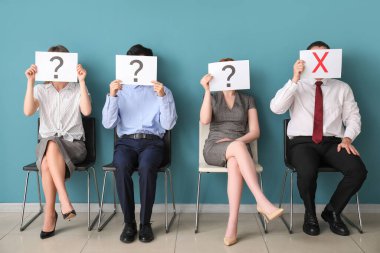 Genç adaylar odada farklı notlarla kağıt çarşaf tutuyorlar.