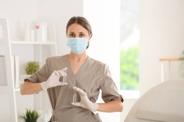 Güzellik salonunda tıbbi maskesi ve ampulleri olan bir kadın kozmetik uzmanı.