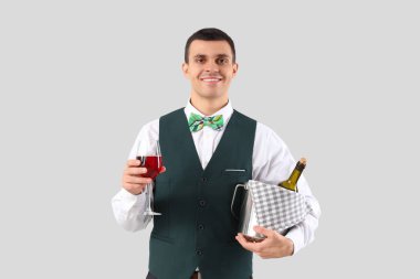 Gri arka planda şarabı olan genç bir garson.