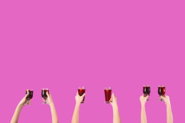 Pembe arka planda sıcak şarap kadehleriyle kadın elleri.