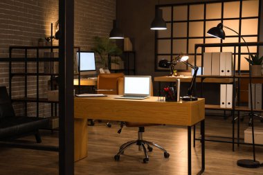 Geceleri masaları ve parlayan lambaları olan karanlık ofisin içinde.