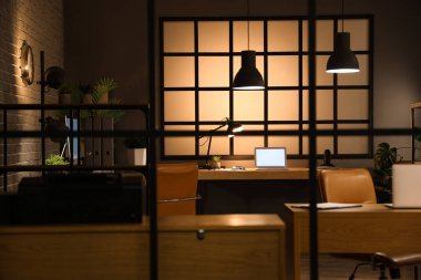 Geceleri masaları ve parlayan lambaları olan karanlık ofisin içi, katlanan ekrandan görünüm