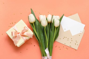 İçinde boş kart, hediye kutusu ve turuncu arka planda beyaz laleler olan zarf.