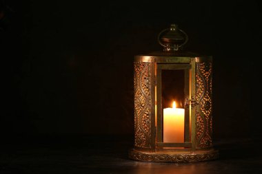 Muslim lamp with burning candle for Ramadan on dark background clipart