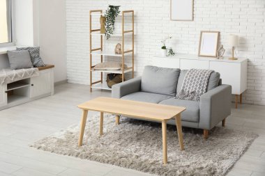 Oturma odasının içinde kanepe, raf ünitesi, çekmeceler ve masa var.