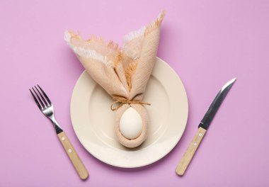 Paskalya yumurtası, peçete ve çatal bıçak ile mor arka planda güzel bir masa.