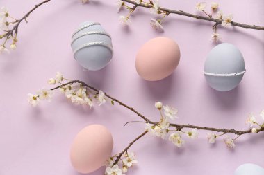 Paskalya yumurtaları ve leylak arka planda çiçek açan dallar. Üst görünüm