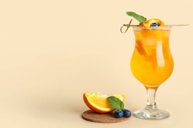 Bej arka planda turuncu ile bir bardak lezzetli kokteyl.