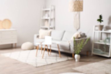 Kanepesi, sehpası ve çiçek açan dalları olan şık bir oturma odası, bulanık bir manzara.