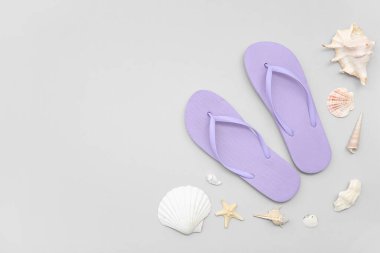 Beyaz arka planda deniz kabukları olan leylak rengi terlikler.