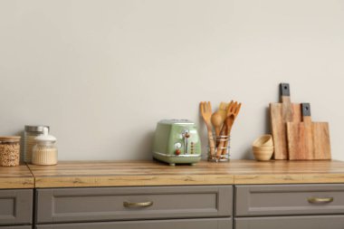 Kahverengi tezgahlı, sebzeli ve tost makineli, bulanık manzaralı bir mutfak.