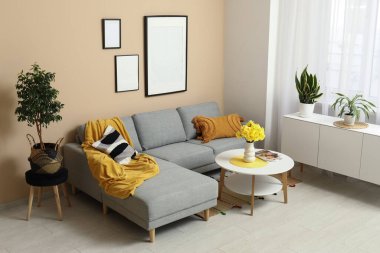 Oturma odasında rahat bir kanepe, sehpa ve vazo çiçekleri var.