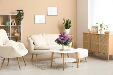 Beyaz kanepenin yanındaki sehpanın üzerinde leylak dalları olan şık bir oturma odası.