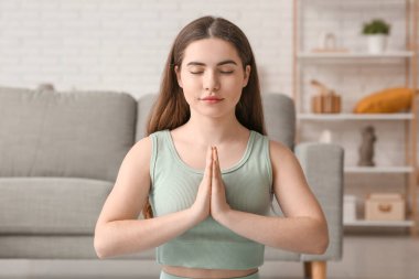 Oturma odasında nefes egzersizi yapan genç ve güzel bir kadın.
