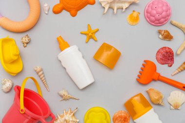 Gri arka plandaki çocuklar için güneş kremi ve plaj aksesuarlarıyla güzel bir kompozisyon
