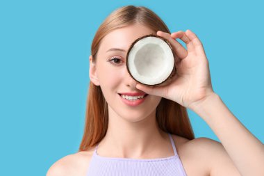 Güzel, genç, mutlu, şık yaz kıyafetleri içinde, mavi arka planda hindistan cevizi olan bir kadın.