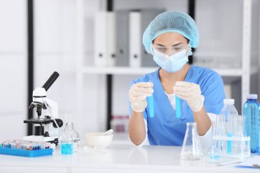 Araştırma laboratuarında profesyonel cam kaplama ve test tüpleri olan genç bir bilim adamı.