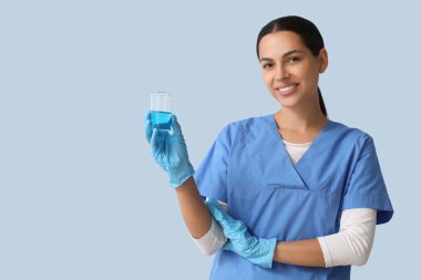 Mavi arka planda su numunesi olan mutlu bayan bilim adamı.