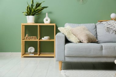 Şık oturma odasında yumuşak yastıklı gri kanepe.