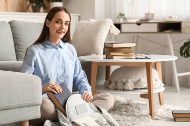 Güzel mutlu kız öğrenci evde sırt çantasına kitap koyuyor.