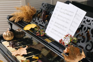 Müzik notaları ve sonbahar dekorasyonlu piyano klavyesi. Yakın çekim.