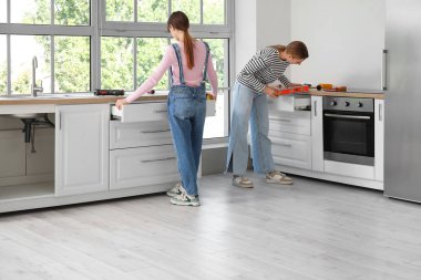 Genç kadınlar mutfakta mobilya topluyor.