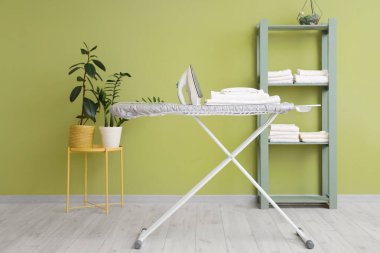 Evde ütü masasında demir ve çarşaf yığını