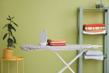 Evde ütü masasında demir ve çarşaf yığını