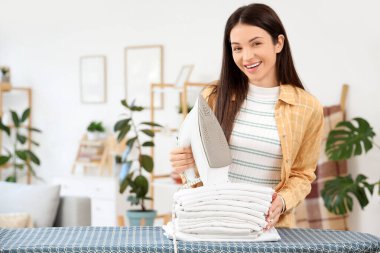 Evinde demir ve beyaz giysileri olan güzel, mutlu bir kadın.