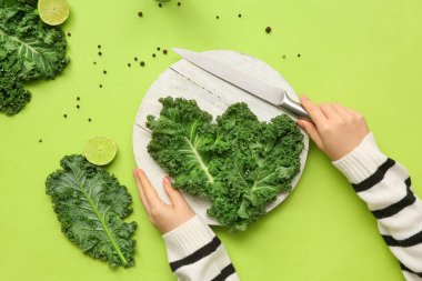 Beyaz ahşap tahta tahtası olan kadın eller yeşil arka planda taze lahana yaprakları ve bıçak
