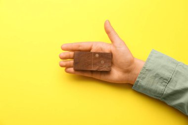 Sarı arka planda tahta domino taşı olan kadın el, yakın plan.
